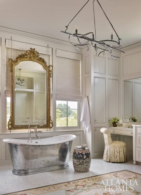 A suspending mirror is the master bath’s focal point. Other winsome details include an antique garden stool and a custom light fixture by Jason Smith of Smithworks Iron & Design.