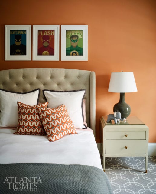 An orange accent wall and framed superhero prints add a jolt of energy to the son’s bedroom.