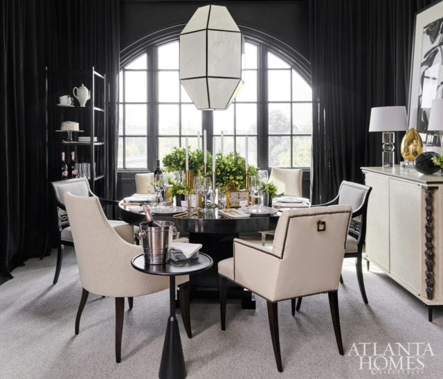 The black-and-white dining room blends vintage mid-century modern pieces, such as the lantern and sideboard, with newer pieces, such as the lacquered dining table, abstract art and brass and bronze sculptures.