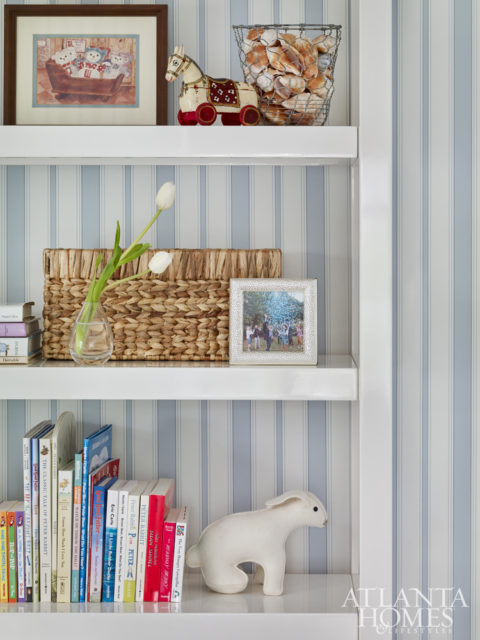 The clean lines of the bookshelves counteract the room’s more traditional elements and offer a spot to display prized items like a print that was once in Lowe’s own nursery as a child.