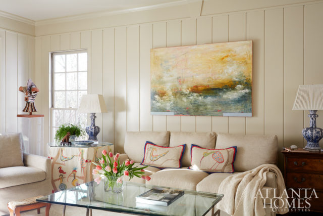 A bird motif, seen on hand-painted pillows and skirted round table from Jerry Pair, lends color to the family room. An abstract work from Pryor Fine Art pops against a Lee Industries sofa and chairs recovered in oatmeal fabric to “play second fiddle to the artwork and, really, the people,” says Jones.