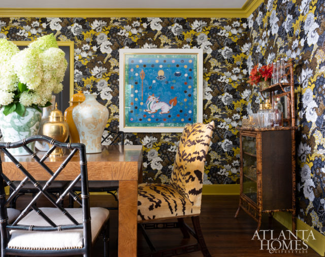 A lively wallcovering from Schumacher and painted moldings add a sense of drama to the formal dining room, which is furnished with a burl table and a mix of vintage chairs.