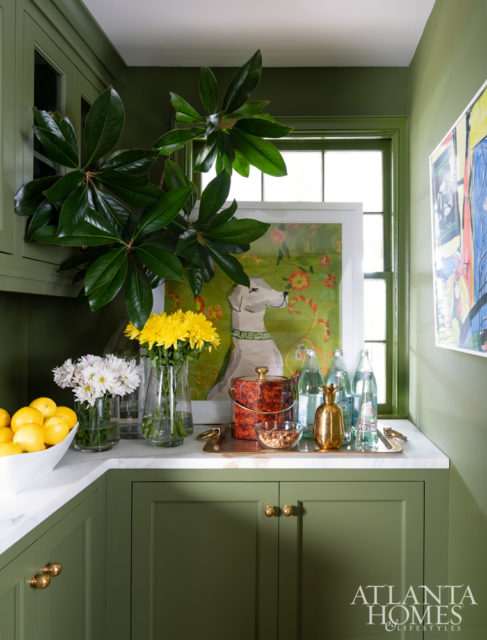 Green walls, moldings and cabinetry define the butler’s pantry.