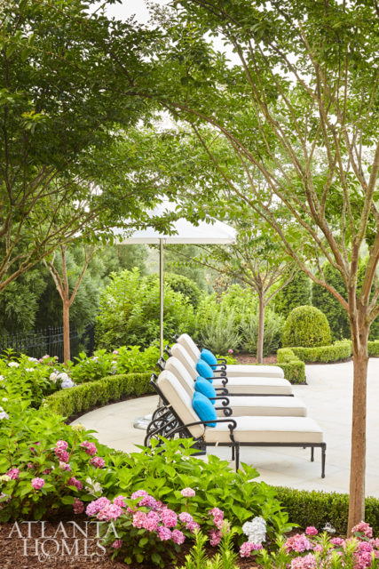 Crepe myrtles cascade over the poolside area, joining an array of hydrangeas. Creekside Nurseries served as the landscape contractor. The chaises and umbrella are from Frontgate.