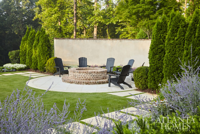 The firepit, set off by a curved wall, serves as a natural destination point for outdoor entertaining. “From the natural world, there are two things that people love. They love water. They love fire,” says Bill Caldwell, director of Harrison Design’s Landscape Architecture Studio.