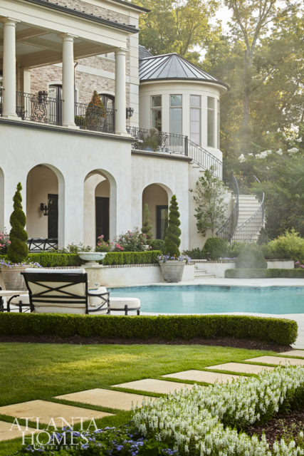 An arched opening on the loggia frames the pool, statue and wooded view on a single axis point, which is a hallmark of European design.