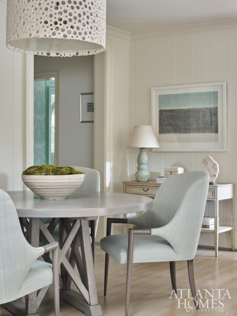 Lighter washed finishes in the breakfast room offer a relaxed and casual feel. Oly’s pierced resin light pendant in a classic drum shape gives the space a dose of whimsy, while artwork by Claudia Thomas also plays up the room’s serene scheme.