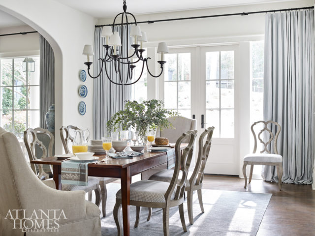 The breakfast room is softened with sinuous chairs with a check fabric from Romo, a pair of upholstered armchairs and an antique table. An iron chandelier keeps the space from feeling too formal.