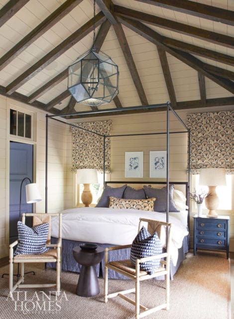 Bedroom with a four-poster bed, beamed ceiling, and patterned window treatments. A large geometric lantern hangs from the ceiling.