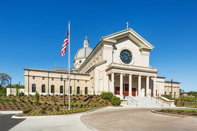 Cathedral of the Most Sacred Heart of Jesus with a large dome, classical columns, and an American flag on a flagpole in front.