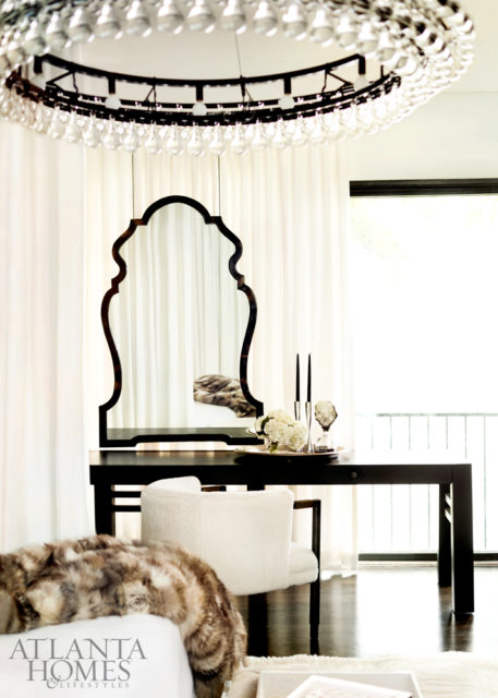 In the master bedroom, with its billowing curtains, walls swathed in hide and a floating mirror, an Ochre chandelier from R Hughes adds another note of glamour. The custom ottoman is by Pfeifer Studio. French animal sculptures, South of Market.