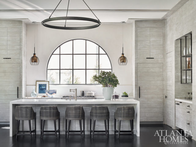 Driftwood adds warmth to the kitchen’s edited aesthetic. The stools are by Palecek and the cage light fixtures are from Lumens.