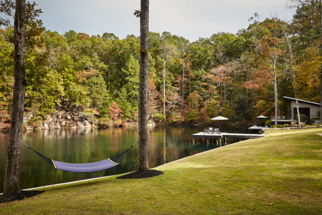 The property offers complete privacy for its owners and guests. Overlooking the lake, with the sound of the waterfall just beyond, Quinn’s tub for MTI Baths takes “forest bathing” to the next level, he says. Landscaping by Matt Fulton of Willow Oaks Landscapes.