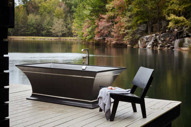 The property offers complete privacy for its owners and guests. Overlooking the lake, with the sound of the waterfall just beyond, Quinn’s tub for MTI Baths takes “forest bathing” to the next level, he says. Landscaping by Matt Fulton of Willow Oaks Landscapes.