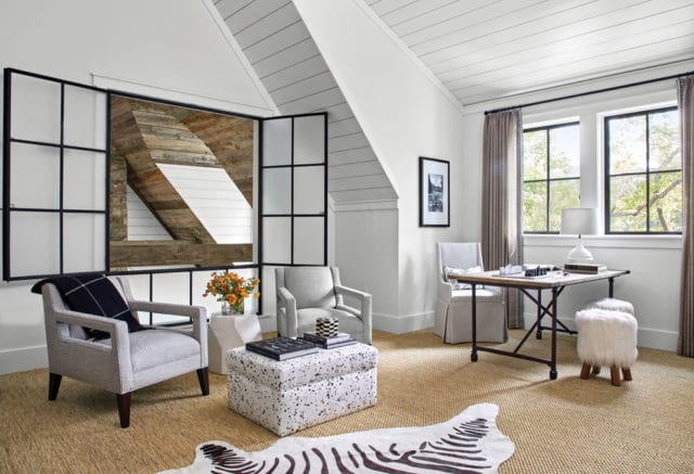 Bright room with sloped ceilings featuring shiplap, two gray armchairs, a white ottoman with black speckles, a desk with a chess set, and a zebra print rug.