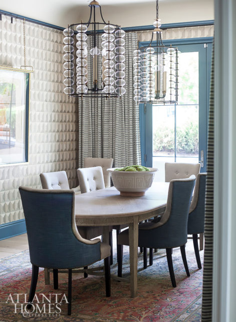 The dining room, which Savage previously designed when the residence played host to the O’More College of Design’s 2017 Show House, is a dramatic departure from its original incarnation. Now, a coffered wood Phillip Jeffries wallcovering adds texture to the walls, while Hermès’ Dune wallpaper adds a gauche effect to a niche. The table is from the homeowners’ own collection, and the drapery is Seemakrish through Paul+. The chandeliers are Paul Ferrante through Ainsworth-Noah.