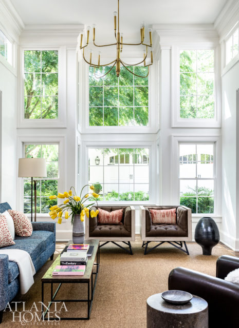 Sunlight streams into the family room, which is where everyone congregates, says Kleinhelter. A pair of tufted chairs upholstered in a Schumacher fabric anchor the space, which is balanced by a rustic coffee table and pair of vintage club chairs in a Kravet leather.