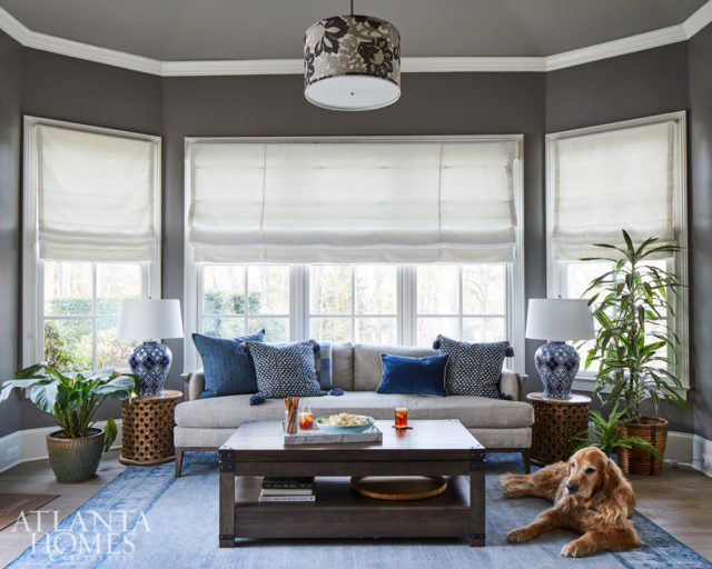 In the rear sunroom, the owner’s well-behaved golden retriever, Toby, lounges next to the light sofa from Brice Ltd. The side tables are from World Market, and the lamps are from Wayfair.