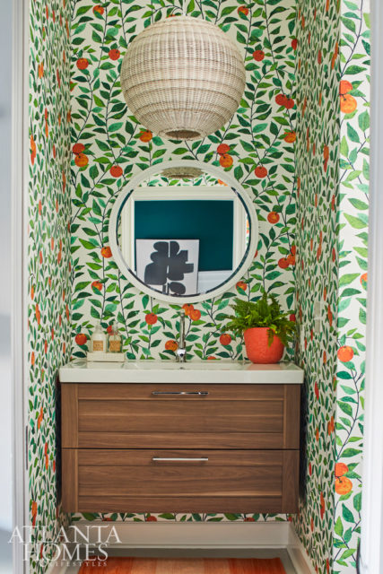 In the nursery bathroom, a vibrant wallcovering depicting oranges adds depth and dimension. The vanity is from IKEA.