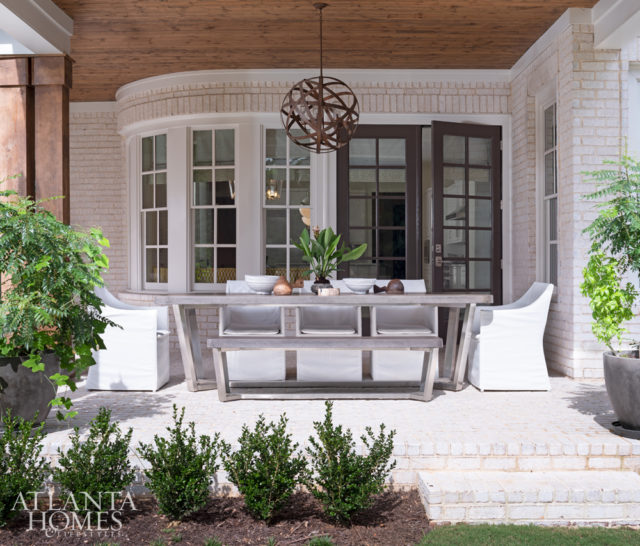 Outdoor armchairs from Artesia pull up to a dining table from Four Hands in the covered outdoor dining area off of the kitchen.