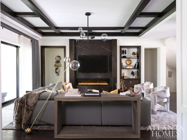 A chandelier from RH illuminates the cozy great room, where a sectional sofa from Natuzzi and club chairs by Moss Studio covered in fabric by Lee Jofa create a comfortable conversation area in front of the newly redesigned fireplace.