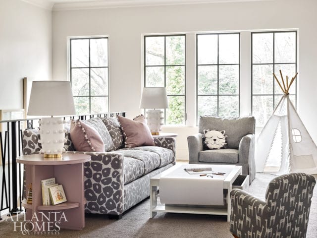 Playroom with a gray leopard print sofa, striped armchair with cat pillow, giraffe print accent chair, white play table, and a teepee