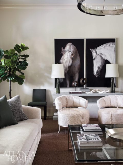 Living room with a cream sofa, two furry accent chairs, and two large black and white horse portraits above a console table.
