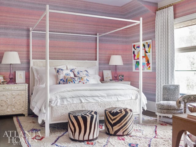 Bedroom with a white canopy bed, pink and purple striped wallpaper, zebra print ottomans, and a leopard print chair.