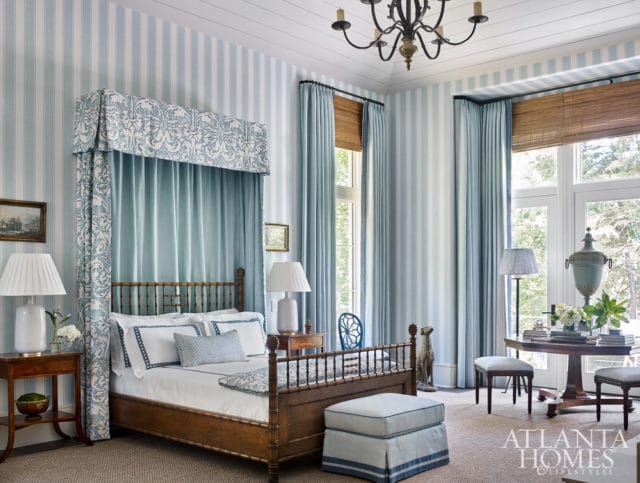 Bedroom with blue and white striped wallpaper, a four-poster bed with a blue canopy, and wooden furniture.