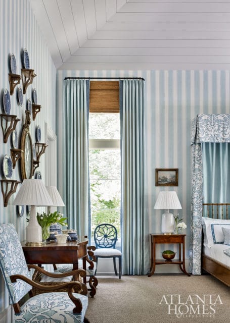 Bedroom with light blue and white striped wallpaper, a four-poster bed with blue and white patterned canopy, and wooden furniture.