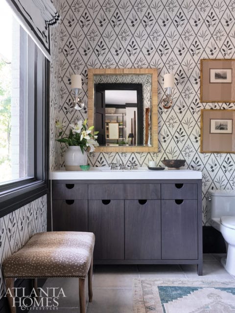Bathroom with dark wood vanity, white countertop, diamond pattern wallpaper, and a deer print upholstered bench. A mirror reflects a closet.