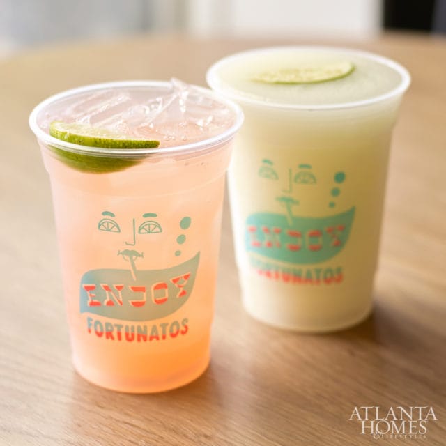 Two plastic cups of drinks with lime slices and "ENJOY FORTUNATOS" logo. One drink is pink, the other is pale yellow.