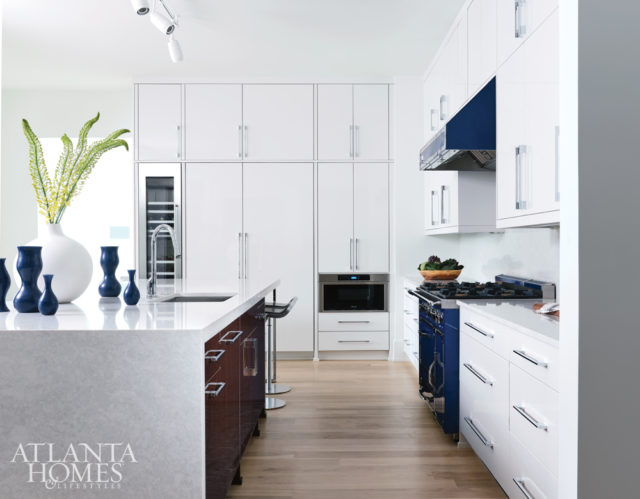 Thermofoil cabinets and a blue Viking Tuscany range and hood energize the kitchen. A floating peninsula on one end of the island adds a tablelike setup.