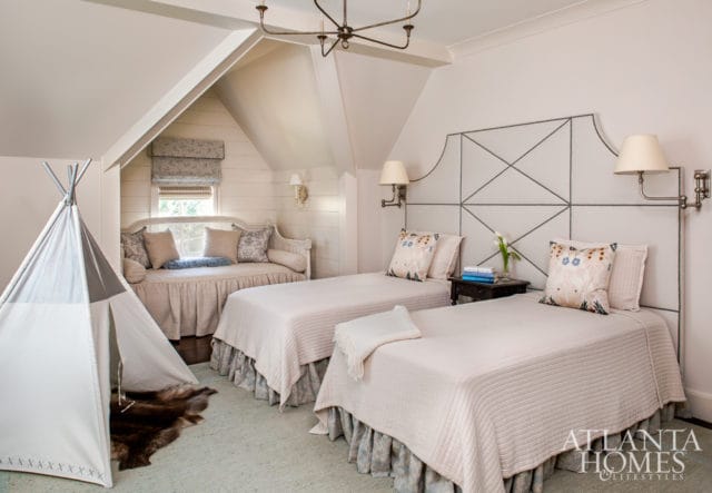 Bedroom with two twin beds, a daybed, and a teepee. The beds have white quilted coverlets and patterned dust ruffles. The daybed is upholstered in a neutral fabric with decorative pillows.