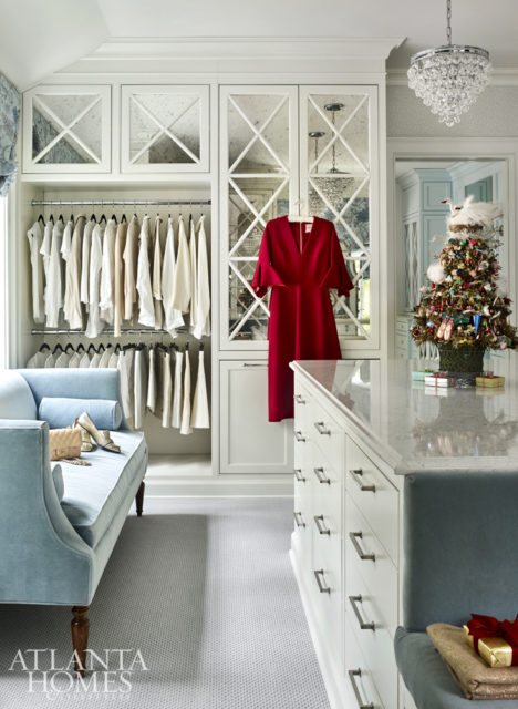 As requested by the owner, the master closet is spacious enough for a quartz-topped center island and a velvet sofa from Wesley Hall. The wallcovering is by Thibaut, and the roman shade is by Larsen Fabrics.