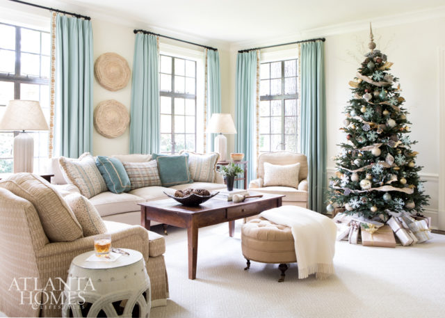 The family room is a study in easy elegance and features a sofa in a C&C Milano fabric, a rug from Patterson Flynn Martin and pillows in Jasper, Justin Van Breda, Cowtan & Tout, and Osborne & Little fabrics. The abaca sculptures over the sofa are from Made Goods. The tree is from Frontgate and the tree skirt is Fig & Dove.