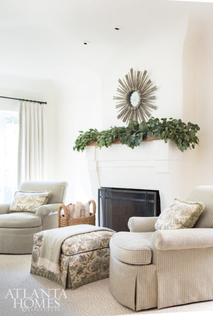 The master bedroom includes matching club chairs and an ottoman and pillows in fabrics from Suzanne Tucker Home through Ainsworth-Noah. The gold Skovde mirror over the mantel is from Acquisitions.