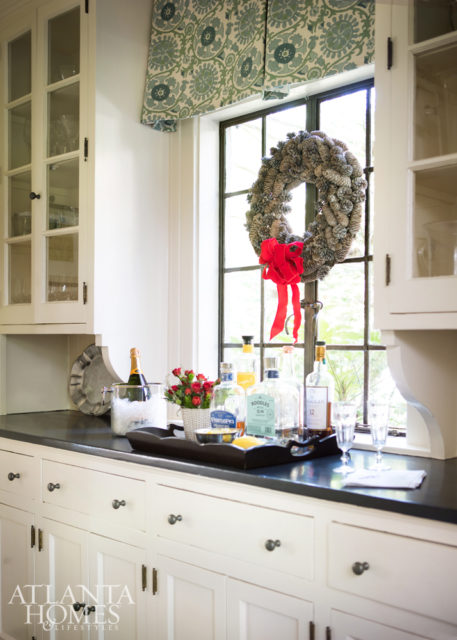 The butler’s pantry is original; Giles added a window treatment to the leaded-glass windows in an aqua-hued Travers print.