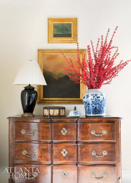 An antique chest in the living room is punctuated by a black lamp and Chinese porcelain filled with ilex berries.