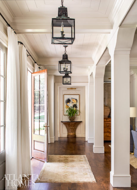 In the front gallery, a gilded antique demilune and abstract painting by Augusta Wilson set against the backdrop of more casual butted wood walls offer a first glimpse of the high-and-low design effect present throughout the home.