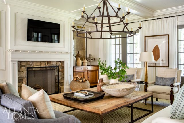 A pair of Visual Comfort iron chandeliers ties together the adjoining living and dining spaces. Pressed foliage by Blackwell Botanicals nod to the home’s natural setting.