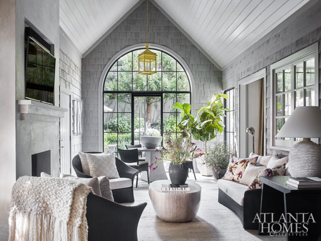 Architect D. Stanley Dixon transformed the home’s screened porch, an addition made more than a decade ago, into an enclosed family room. The new arched iron window provides an improved visual connection to the backyard. The Pouf coffee table is Caste through R Hughes and the lantern is The Urban Electric Co.