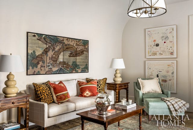 Living room with a plaid sofa, leopard print and patterned throw pillows, a large Asian-inspired screen artwork, and two abstract paintings on the wall.