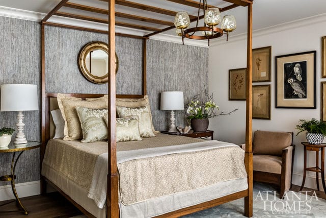 Bedroom with a wooden four-poster bed, textured gray wallpaper, and framed botanical prints on the wall.