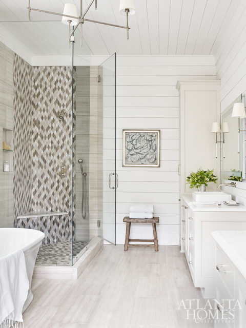 A water-jet glass mosaic shower tile complements the brushed limestone flooring from Renaissance Tile & Bath in the master bathroom. The bench is from B.D. Jeffries.