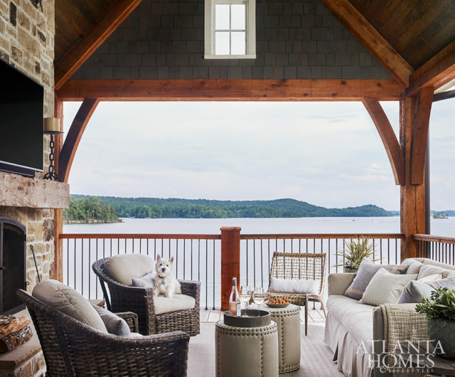 An outdoor sofa and chairs, all from Logan Gardens, invite lakeside conversations on one of the home’s covered porches. The stools with nailhead trim are Lee Industries.