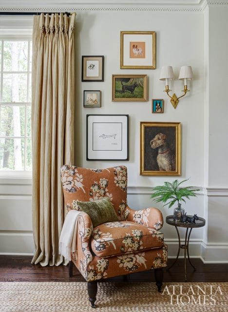 Living room corner with patterned armchair, dog-themed artwork gallery wall, and striped curtains.