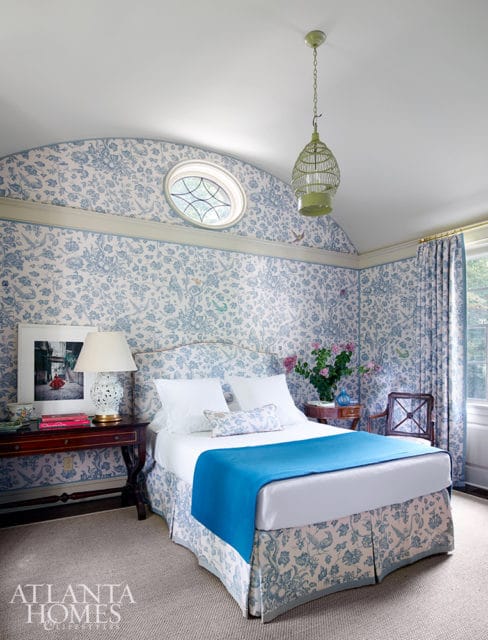 Bedroom with blue and white floral wallpaper, a white bed with blue accents, and a green birdcage chandelier.