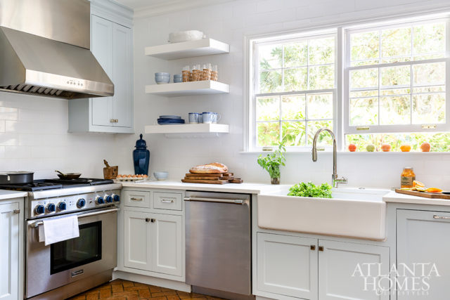 White subway tiles, open shelves and a large farmhouse sink create an authentic environment.