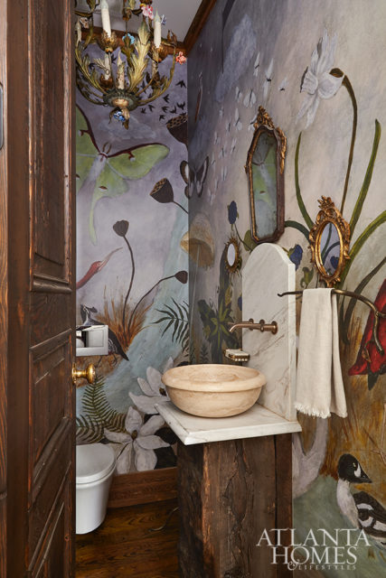 A fanciful mural-style wallpaper from Anthropologie adds panache to the petite powder room.